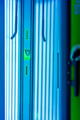 Solarium empty tanning bed in modern beauty salon, view from inside with closed lid and all light bulbs glowing on