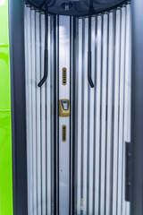 Solarium empty tanning bed in modern beauty salon, view from inside with closed lid and all light bulbs glowing on
