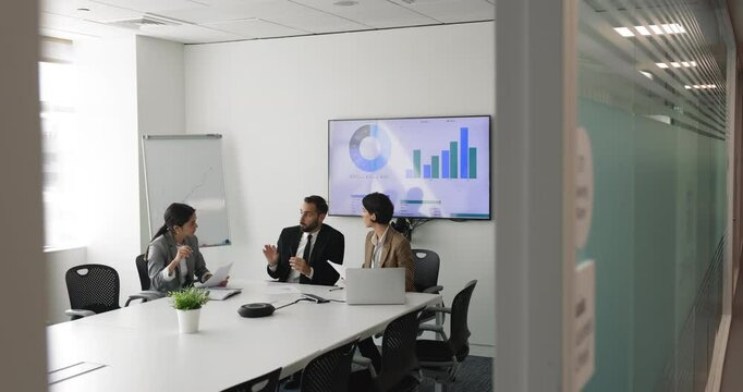 Multi-ethnic staff take part in group briefing seated at table in modern conference room engaged in teamwork and collaboration, discussing sales data, forecasting, reviewing reports, analyzing data