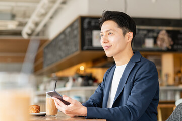 カフェでスマホを見るミドルの男性
