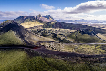 Stunning aerial image showcasing a volcanic crater surrounded Landmannalaugar mountains and by hills and expansive wilderness, emphasizing the raw beauty and geology of volcanic regions in Iceland
