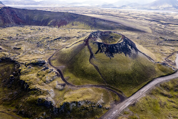 Stunning aerial image showcasing a volcanic crater surrounded Landmannalaugar mountains and by hills and expansive wilderness, emphasizing the raw beauty and geology of volcanic regions in Iceland