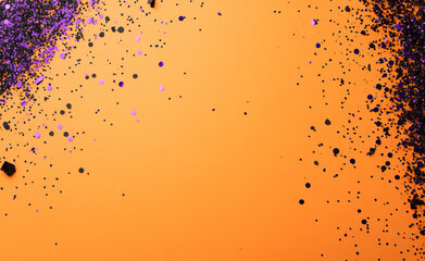 A minimalistic Halloween-themed background with an orange backdrop, scattered purple and black confetti, and an empty space on the right, perfect for seasonal designs and party invitations.