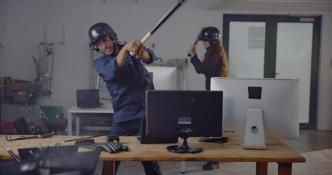Rage room, anger and people with computer smash for stress relief, emotional release and equipment vandalism. Friends, safety gear and destroy tech with baseball bat for frustration and vent activity