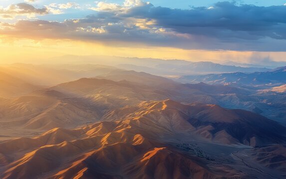 Aerial view of mountains and hills during golden sunset with blue skies and clouds