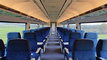 Fototapeta premium Empty train carriage with blue seats and rural landscape view
