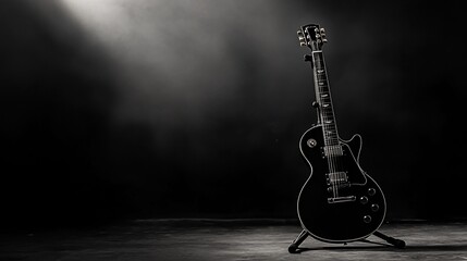 Naklejka premium Black electric guitar on stand, dramatically lit against dark background.