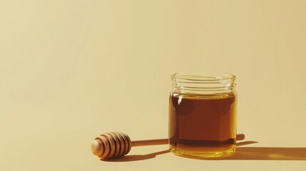 Golden honey in a glass jar with a wooden honey dipper.