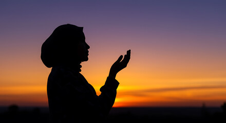 Fototapeta premium Silhouette Of Muslim Woman Praying At Sunset During Ramadan