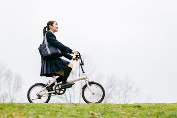 Fototapeta premium 自転車通学する制服姿の中学生・高校生の女の子 