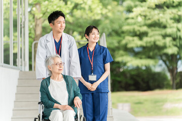 Obraz premium 病院・介護施設にいる車椅子に乗った高齢者と医師・看護師 