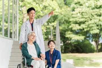 病院・介護施設にいる車椅子に乗った高齢者と医師・看護師
