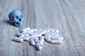cápsulas de fármacos junto a una calavera gris