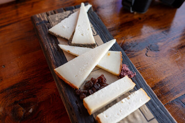 Tasting of Spanish cheeses made on Canary islands, goat cheese, smoked and triangles of manchego curado cheese on wooden plank