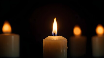 A solitary candle flame glowing softly in a dark space