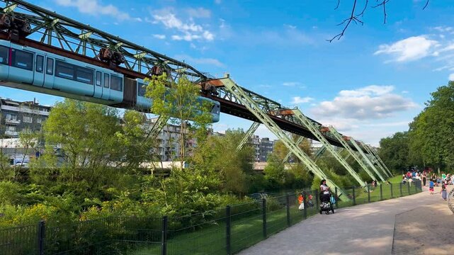 Train car moves on monorail suspended on overpass of Wuppertal Suspension Railway. Public transport metropolitan in Wuppertal, North Rhine Westphalia, Germany July 29, 2024. High quality 4k footage