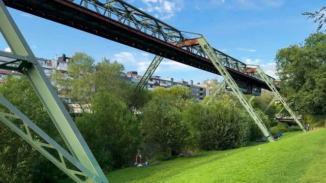 Train car moves on monorail suspended on overpass of Wuppertal Suspension Railway. Public transport metropolitan in Wuppertal, North Rhine Westphalia, Germany July 29, 2024. High quality 4k footage