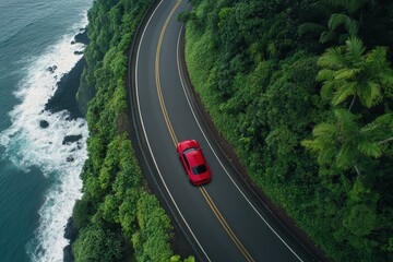 Aerial View of a Red Car Driving Along a Scenic Coastal Road Surrounded by Lush Greenery