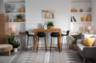 Dining table, chairs and sofa in cozy room, blurred view. Interior design