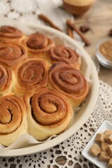 Freshly baked cinnamon rolls and brown sugar cubes on table, closeup