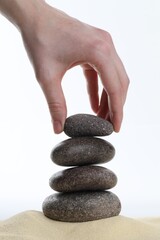 Woman making stack of stones on white background, closeup. Harmony and life balance