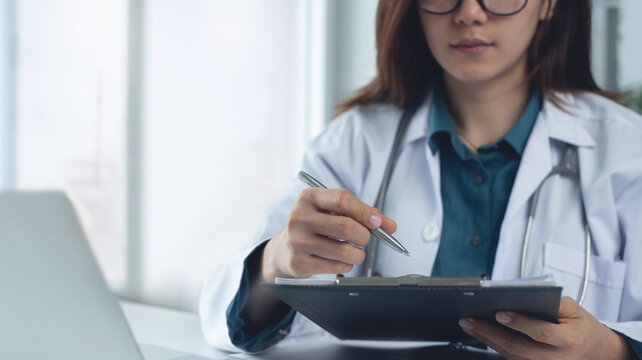 Closeup, female doctor filling medical chart, checklist document, patient's information on clipboard. Doctor writing, signing on health insurance document in hospital, healthcare and medicine concept