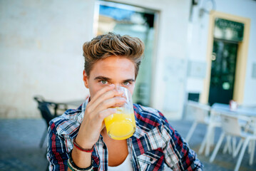Young man drinking orange juice at outdoor cafe
