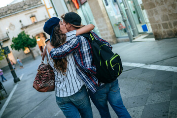Young couple kissing in a city street while walking