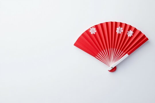 Red fan with white flowers on it is on a white background