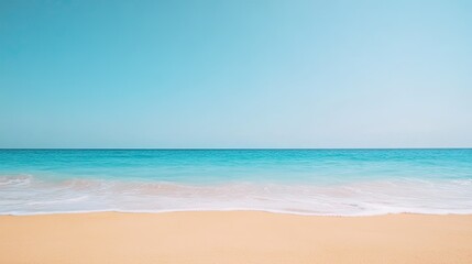 Obraz premium Serene beach landscape showcasing soft waves lapping against golden sand under a clear blue sky