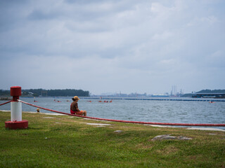 Woman Sits Reflectively by the Water While Others Kayak in the River