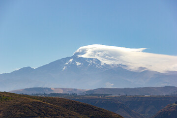 Fototapeta premium Vista del volcán Cayambe en día despejado y soleado, se aprecia nubes sobre la cima.