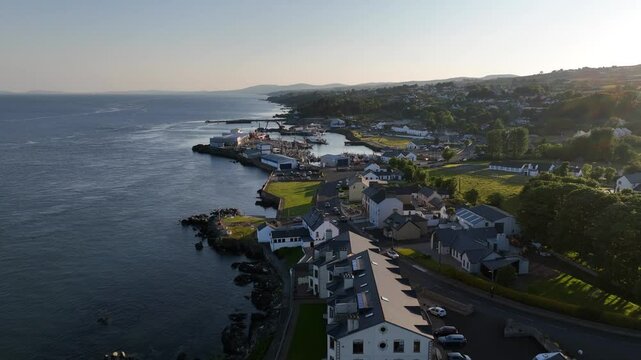 Lough Foyle Ferry, County Donegal, Ireland, June 2023. Drone pushes forwards towards Greencastle Harbour as vessel arrives and docks against the quay in the soft evening light.