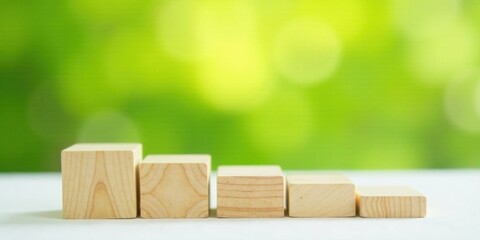 Wooden blocks ascending in size against a blurred green backdrop, symbolizing growth and progress