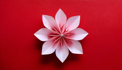 Origami art; handmade paper flower on red background, top view