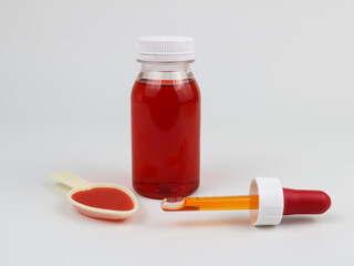 Cough syrup bottle, dropper and dosing spoon on white background. Cough medicine concept