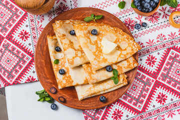 Pancakes with honey and berries on the table next to the samovar