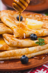 Pancakes with honey and berries on the table next to the samovar