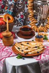 Pancakes with honey and berries on the table next to the samovar