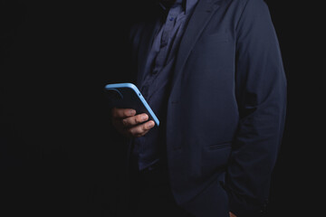 man in suit holding smartphone in dark setting