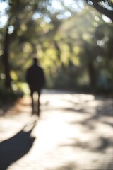 Obraz premium Blurred silhouette of a person walking through a sunlit park on a peaceful day : Generative AI