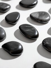 Polished black stones arranged in rows on a white background.