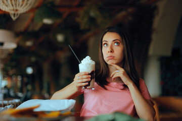 Surprised Woman Holding a Whipped Cream Coffee Beverage. Health conscious person counting calories while sipping a drink
