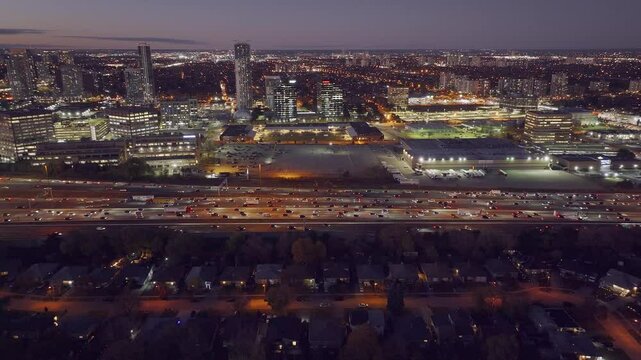 Highway 401 and 404 intersection in Ontario at dusk, with heavy traffic and city lights