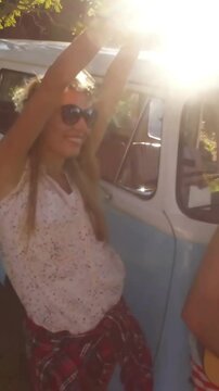 Man playing guitar in campervan and friends dancing beside him