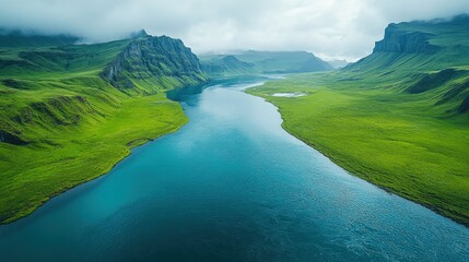 Aerial view of a serene river winding through lush green valleys under a cloudy sky