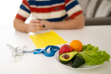 An individual carefully planning nutritious meals using various fresh produce and several measuring tools