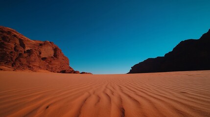 Naklejka premium Majestic desert expanse under azure sky with colossal rock formations flanking the dunes