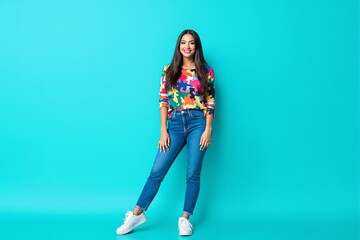 Young woman wearing a vibrant puzzle-patterned sweater and jeans posing confidently against a blue background. Fashion, confidence, and modern style concept. Ai generative