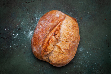 Rustic whole grain wheat sourdough bread. Green table background, top view
